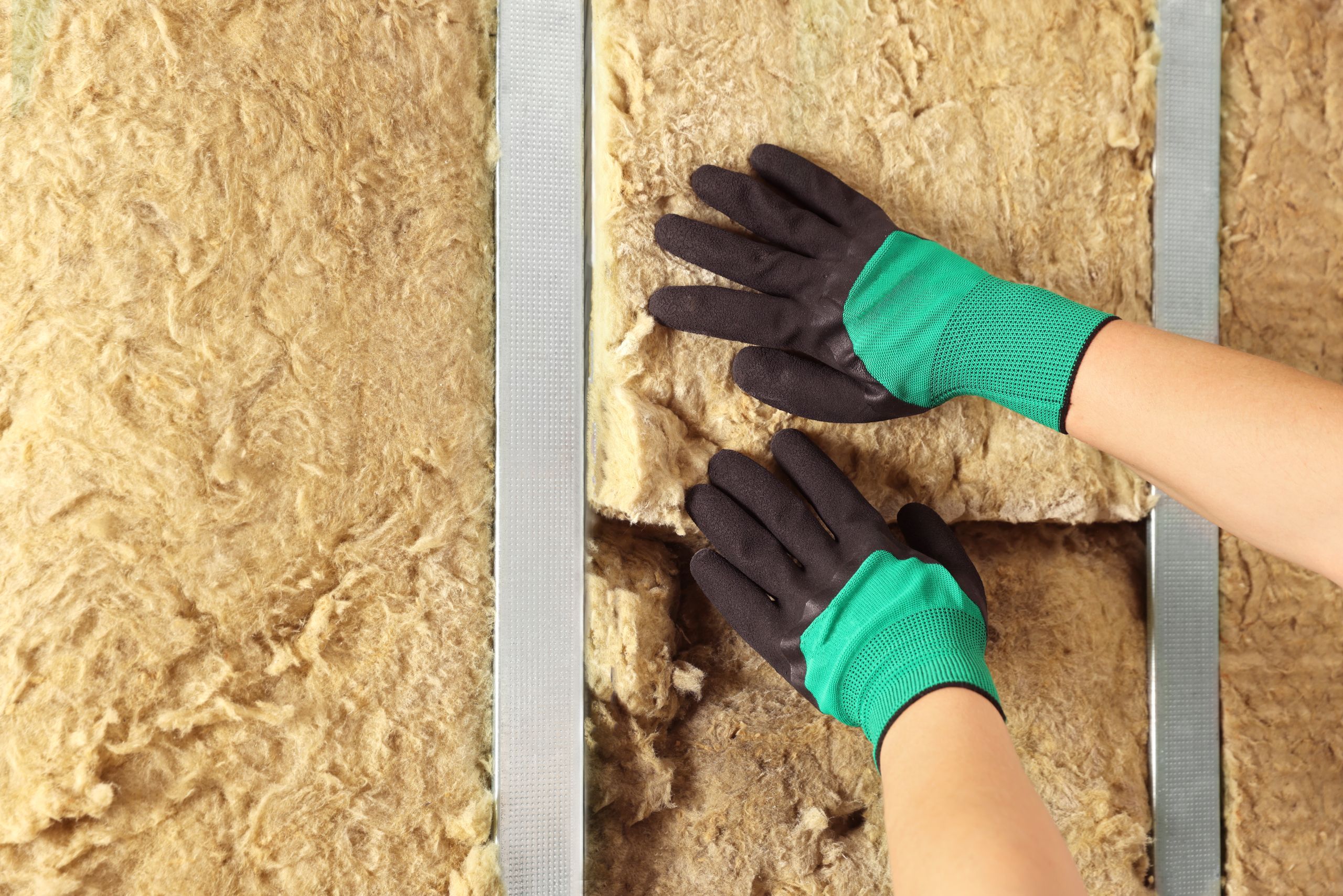 Handwerker verlegt Dämmmaterial an der Wand