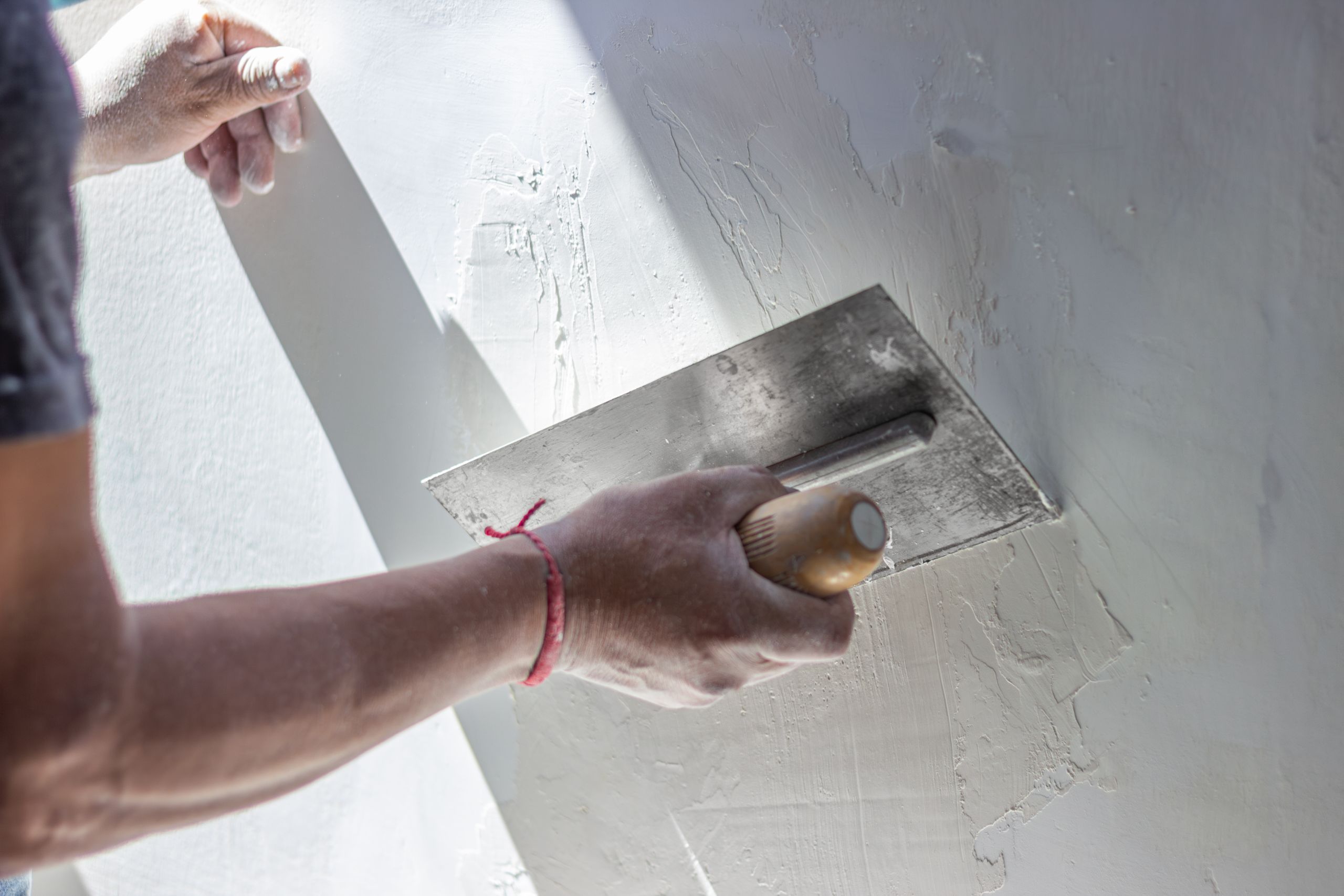 Stuckateur verputzt eine Wand mit der Glättkelle